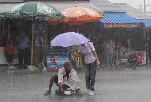 น้ำใจงาม! สาวจีนกางร่มบังสายฝนให้ชายชราขาพิการ 