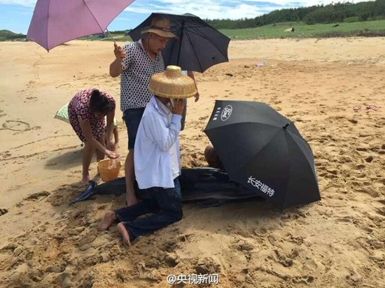ชาวบ้านยืนกางร่มให้โลมาที่เกยหาด