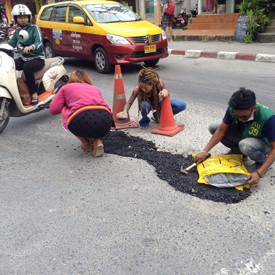 หญิงสาวควักเงินซื้อยางมะตอยซ่อมถนน