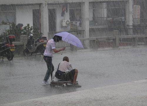 น้ำใจงาม! สาวจีนกางร่มบังสายฝนให้ชายชราขาพิการ 