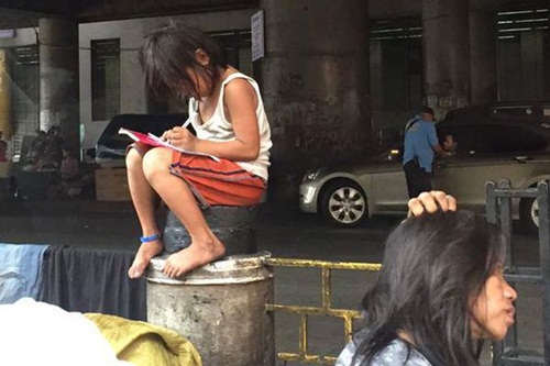 เด็กหญิงคนนี้ทำการบ้านบนเสาคอนกรีตริมถนน